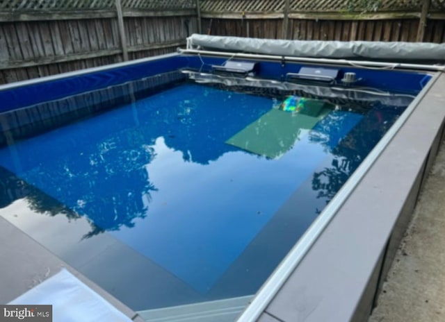 view of swimming pool with a hot tub and a fenced backyard