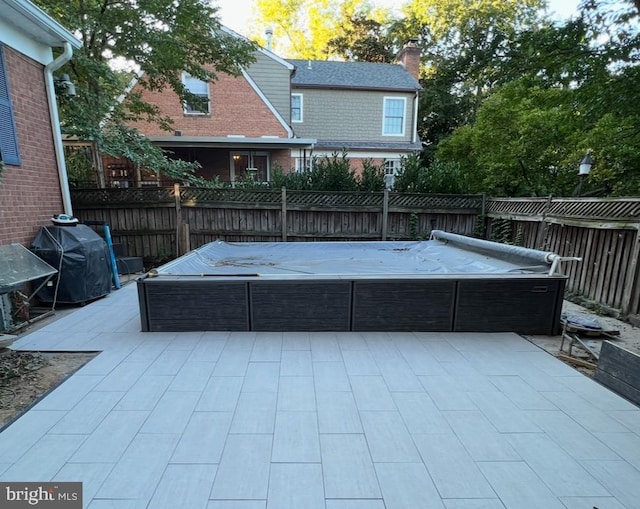 view of patio with a hot tub, a grill, and fence