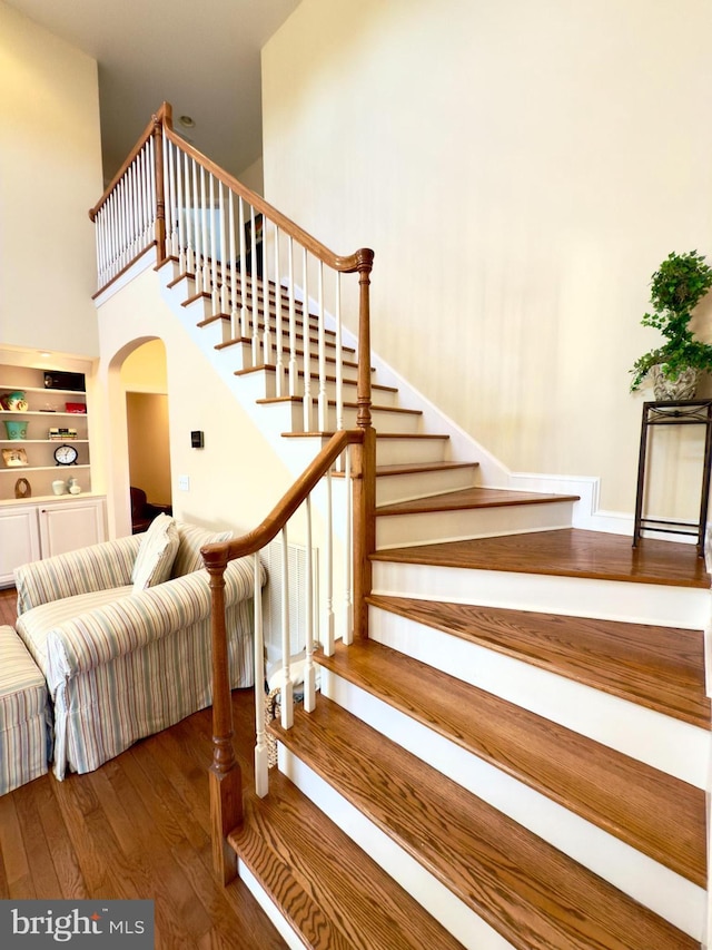 staircase featuring hardwood / wood-style flooring and a high ceiling