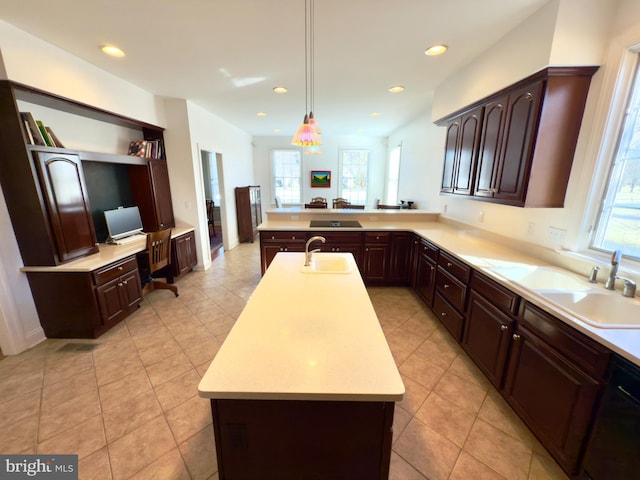 kitchen with hanging light fixtures, sink, kitchen peninsula, and an island with sink