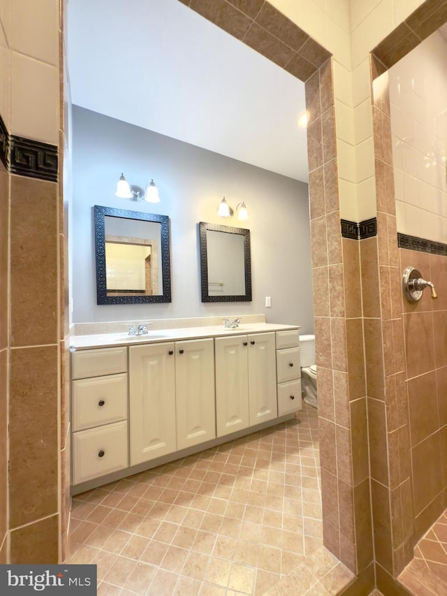 bathroom with vanity, tiled shower, and toilet