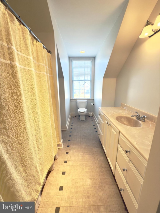 bathroom with vanity, vaulted ceiling, and toilet