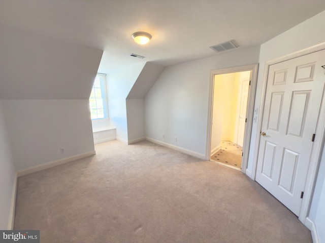 additional living space featuring vaulted ceiling and light carpet