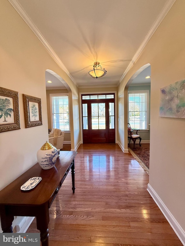 entrance foyer featuring crown molding, plenty of natural light, and hardwood / wood-style floors