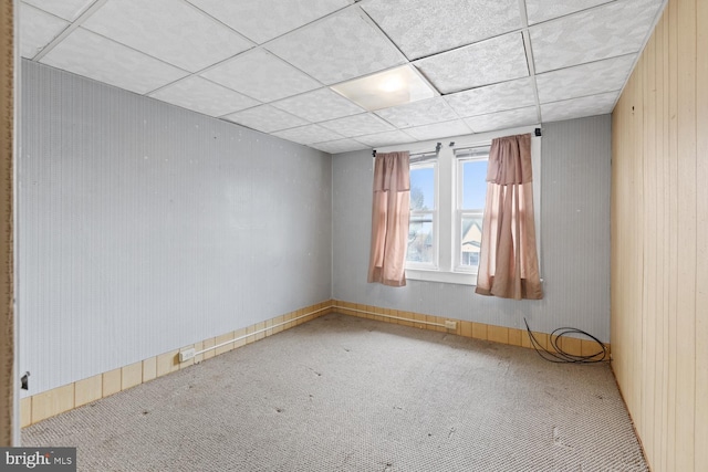 carpeted empty room featuring a paneled ceiling