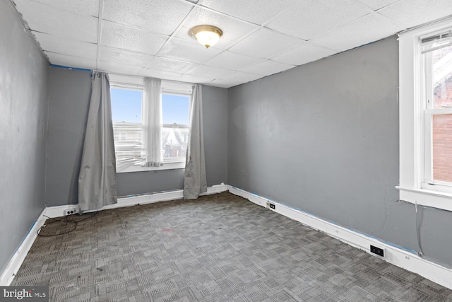 carpeted empty room featuring a drop ceiling