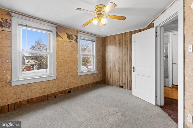 unfurnished bedroom with ceiling fan and dark colored carpet