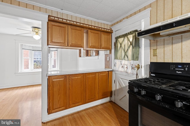 kitchen featuring crown molding, ceiling fan, light hardwood / wood-style floors, and black gas range oven