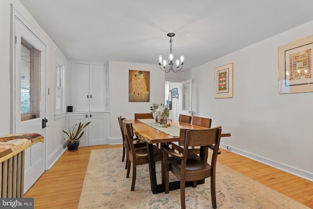 dining space featuring a chandelier, light wood-type flooring, and baseboards