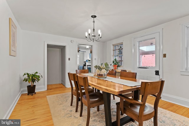 dining area featuring a chandelier, light wood finished floors, and baseboards