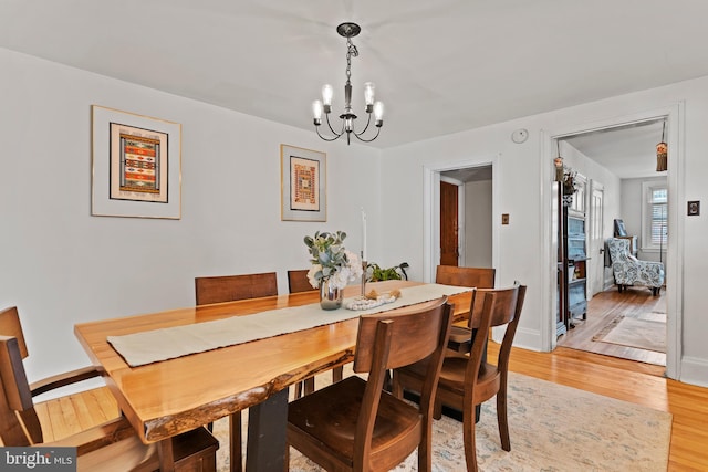 dining area with a chandelier, light wood-type flooring, and baseboards