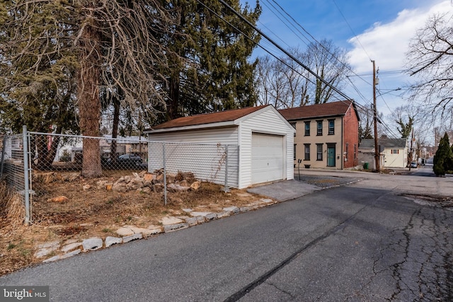 detached garage featuring fence and aphalt driveway