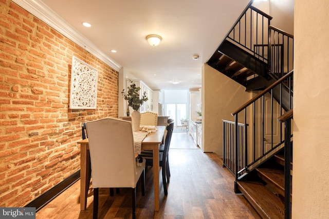 dining area featuring stairs, crown molding, brick wall, and wood finished floors