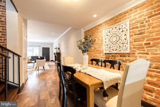 dining area with brick wall, crown molding, stairway, and wood finished floors