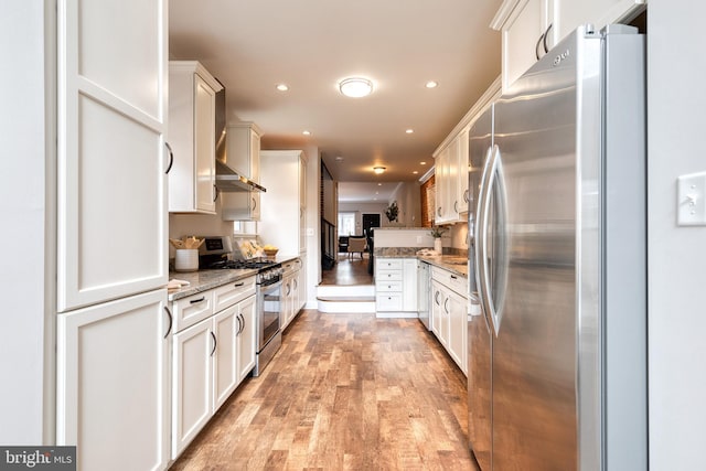 kitchen featuring stainless steel appliances, white cabinetry, light stone counters, and light wood finished floors