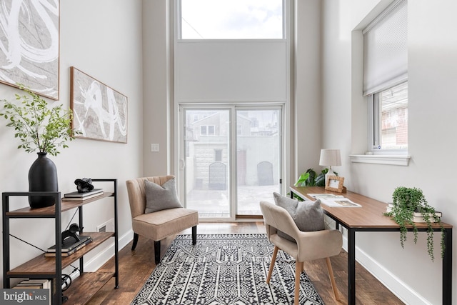 office area with dark wood finished floors, a towering ceiling, and baseboards