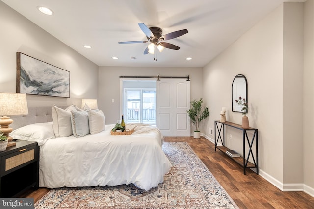 bedroom featuring recessed lighting, a barn door, baseboards, and wood finished floors