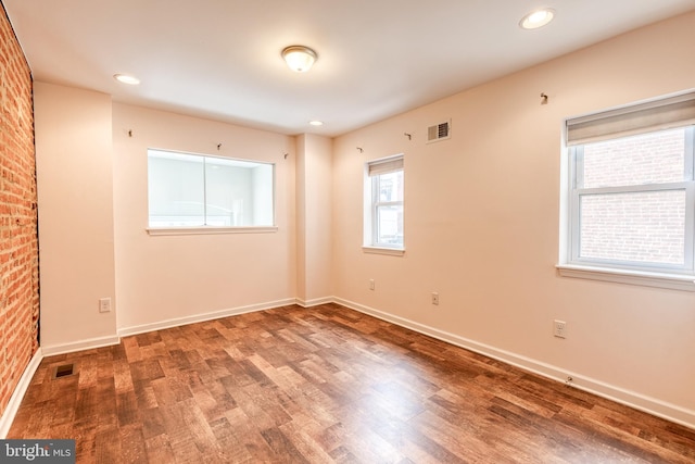 unfurnished room featuring wood finished floors, visible vents, and baseboards