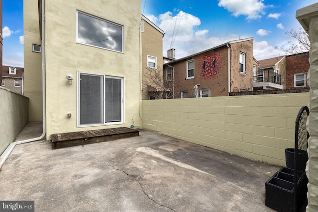 rear view of house with a patio area, fence, and stucco siding