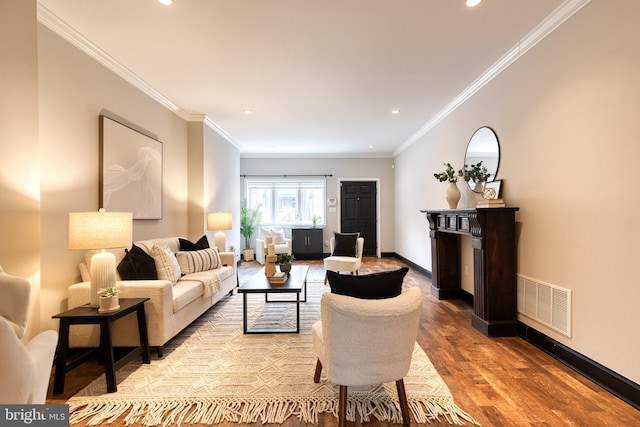 living area featuring ornamental molding, wood finished floors, visible vents, and baseboards