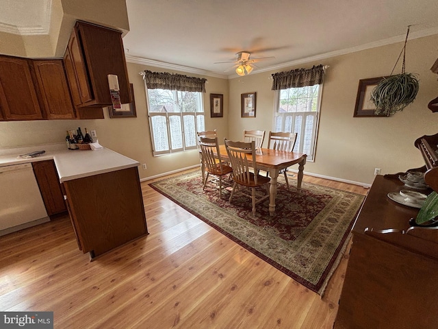 dining area with ceiling fan, light wood-type flooring, baseboards, and crown molding