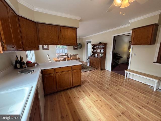 kitchen featuring a peninsula, light wood finished floors, brown cabinetry, and light countertops