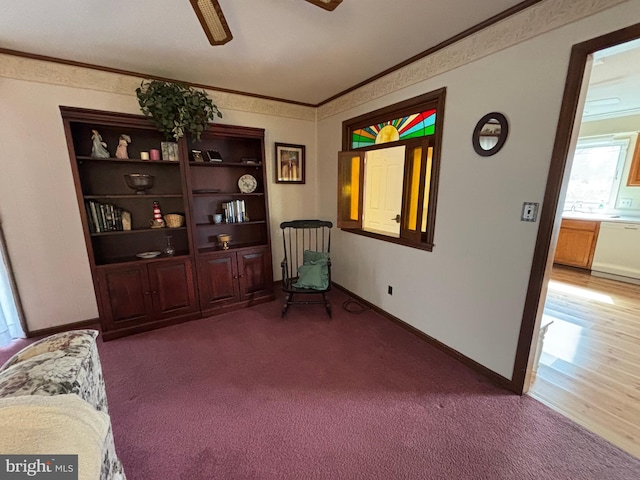 sitting room featuring a ceiling fan, carpet flooring, crown molding, and baseboards