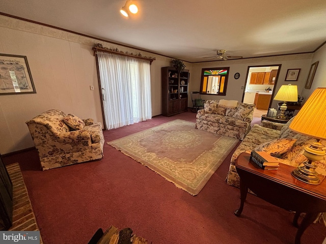 living area featuring carpet floors, ornamental molding, and a ceiling fan