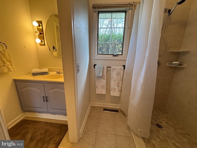 full bath with tile patterned flooring, vanity, visible vents, baseboards, and tiled shower