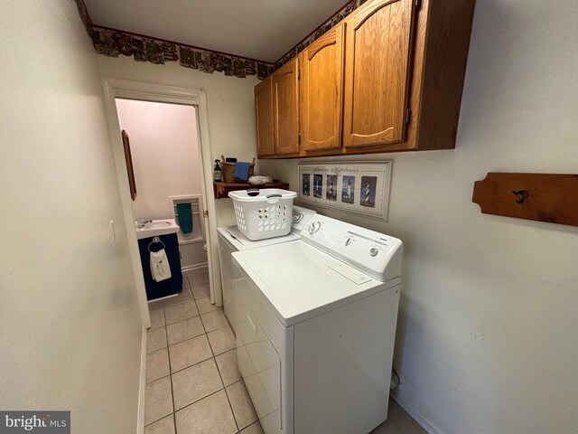 washroom with light tile patterned floors, a sink, washing machine and clothes dryer, and cabinet space