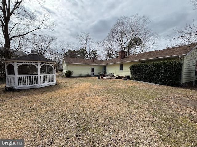 rear view of property featuring a yard and a chimney