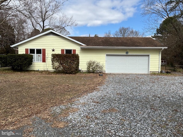 single story home with gravel driveway, roof with shingles, and an attached garage