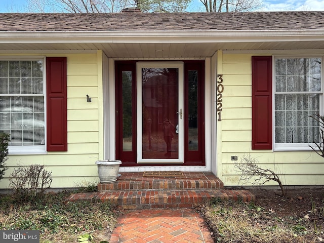 doorway to property featuring roof with shingles