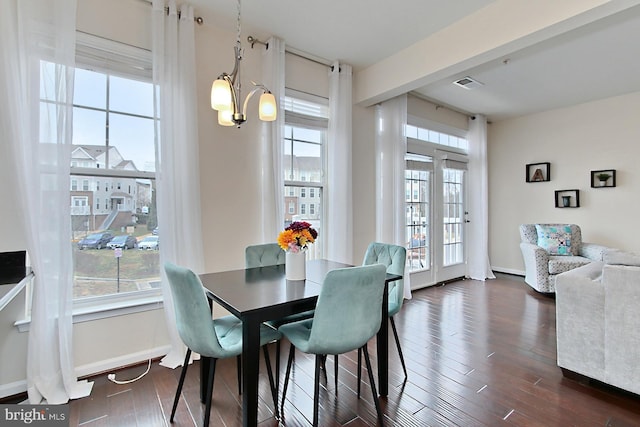 dining area featuring dark wood-type flooring and an inviting chandelier