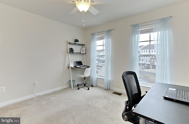 office space with light carpet, ceiling fan, and a healthy amount of sunlight