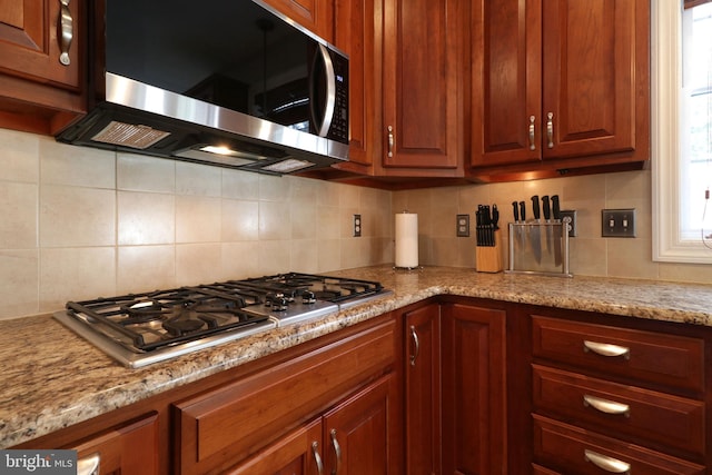 kitchen with stainless steel appliances, light stone counters, and tasteful backsplash