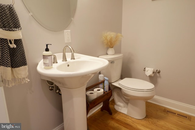 bathroom with baseboards, visible vents, toilet, and wood finished floors