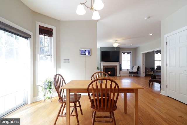 dining area featuring light wood finished floors, a fireplace with flush hearth, and baseboards