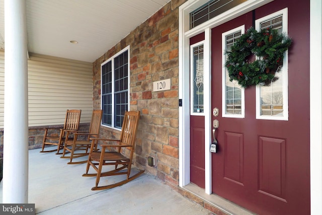 entrance to property featuring stone siding and a porch