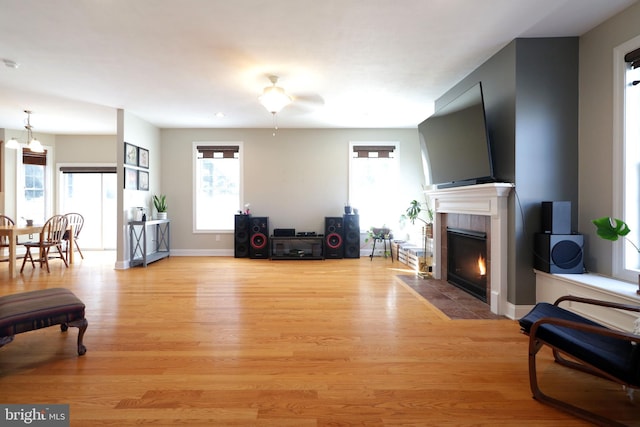 living area featuring light wood-style floors, a tile fireplace, and a wealth of natural light