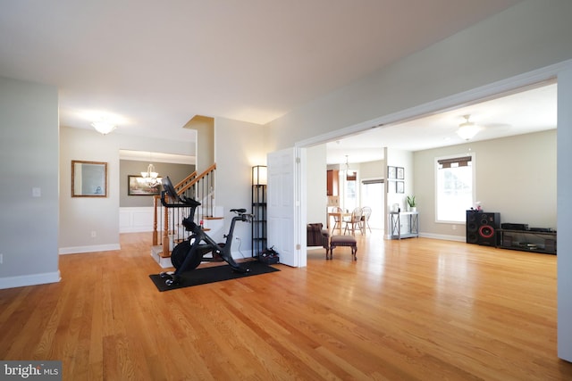 workout room with a chandelier, light wood-type flooring, and baseboards