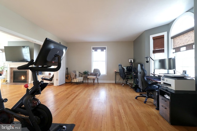 office space featuring light wood-type flooring, a fireplace with flush hearth, and baseboards