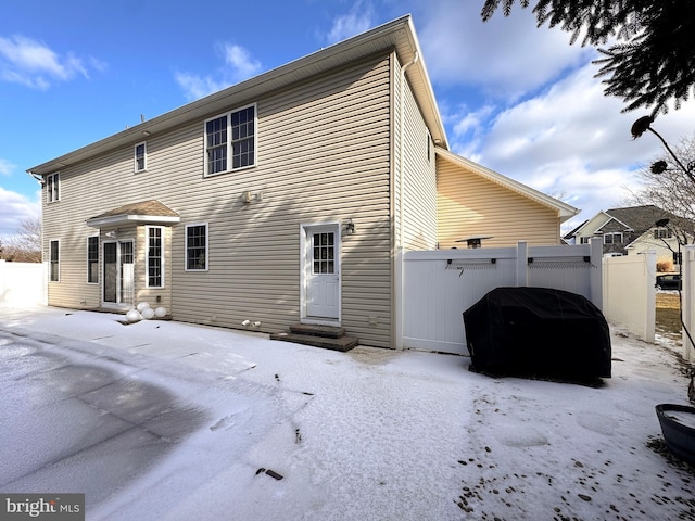 rear view of house featuring entry steps and fence