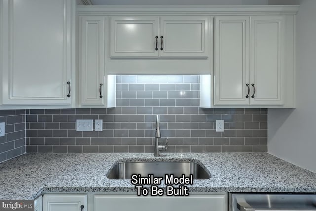 kitchen with light stone countertops, sink, and white cabinets