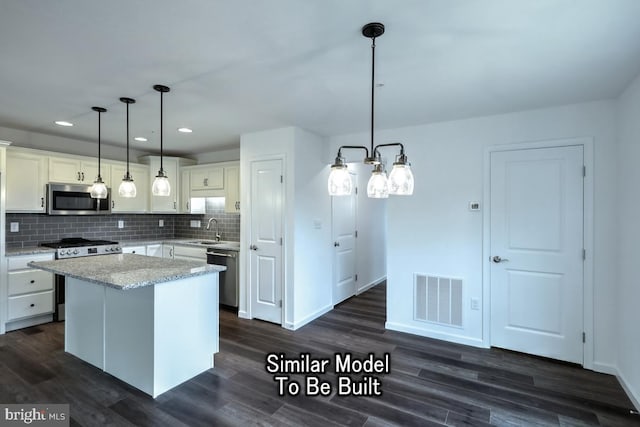 kitchen with a kitchen island, appliances with stainless steel finishes, sink, and pendant lighting