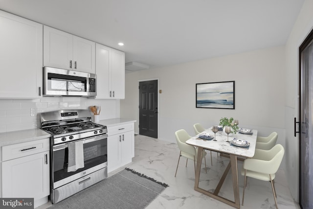 kitchen featuring stainless steel appliances, white cabinets, and decorative backsplash