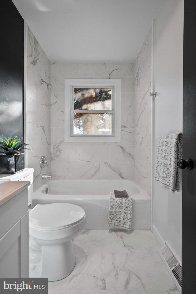 full bathroom featuring vanity, tiled shower / bath combo, and toilet