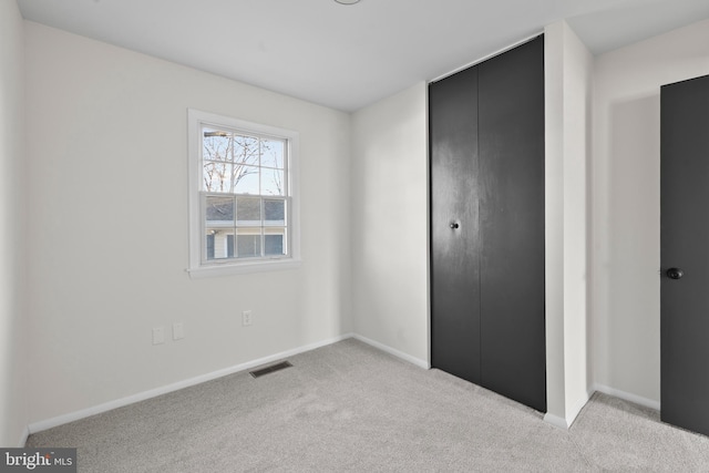 unfurnished bedroom featuring light carpet and a closet