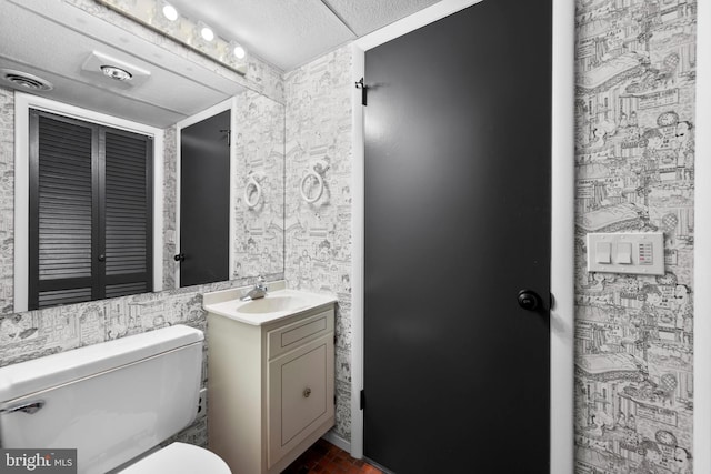 bathroom with vanity, toilet, and a textured ceiling