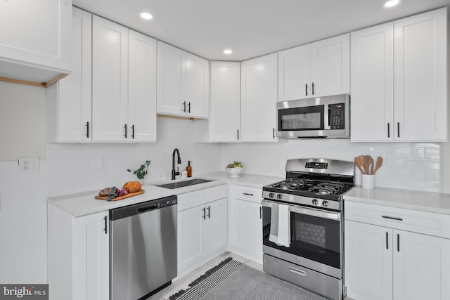 kitchen featuring sink, decorative backsplash, white cabinets, and appliances with stainless steel finishes